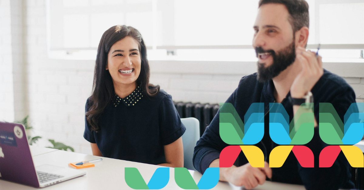 Two team members smiling and chatting in an office