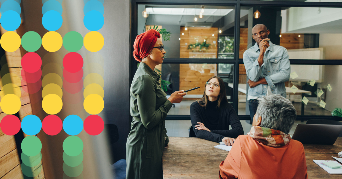 4 team membesr in thought at a table in an office while a woman in the group is presenting