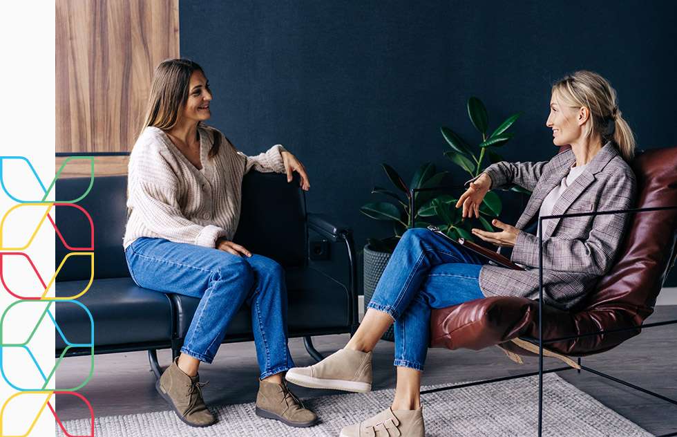 Two woman sit across from each other in discussion.