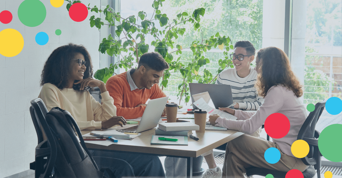 4 people sitting around a table in a meeting at an office with plants in the background
