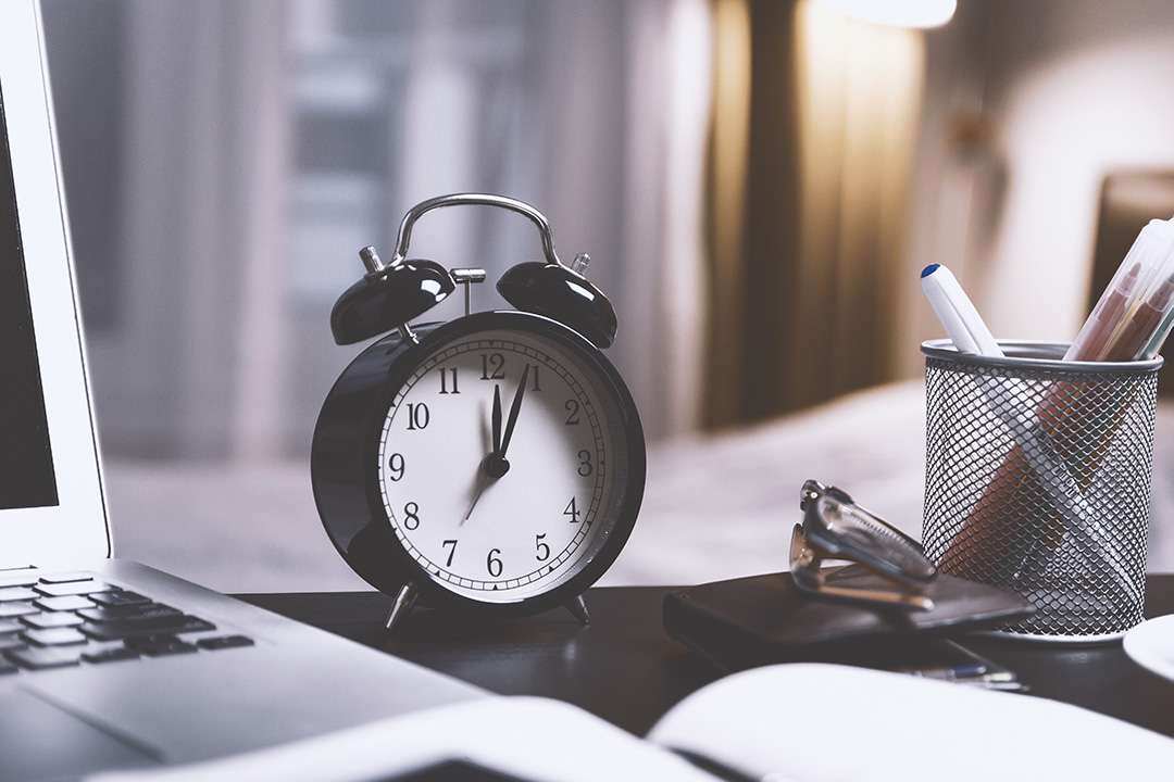 Clock on a desk next to a laptop
