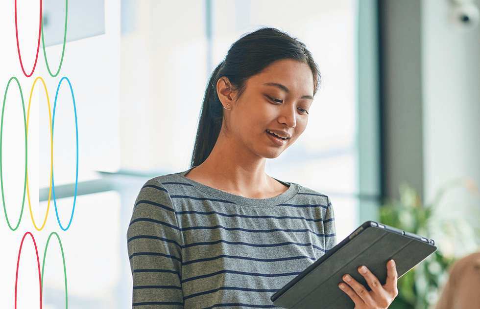 Women smiling while looking at a tablet in the office