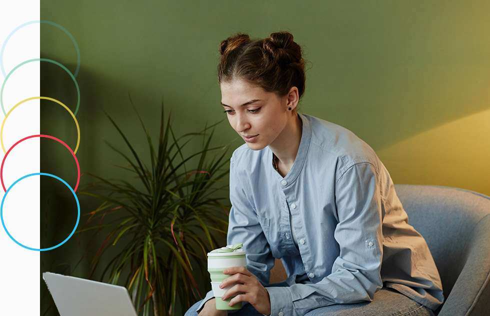 A woman with a coffee sitting in a office on her laptop