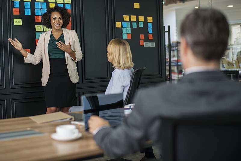 Woman presenting sticky notes on a board in a team meeting